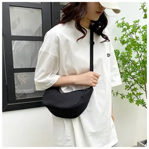 Side view of black nylon crescent crossbody bag on model for daily casual outfit