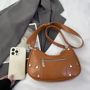 Vintage brown leather rivet dumpling bag with silver hardware and adjustable strap