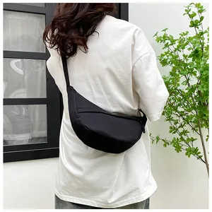 Rear view of model wearing a minimalist black nylon crescent crossbody bag in a casual setting