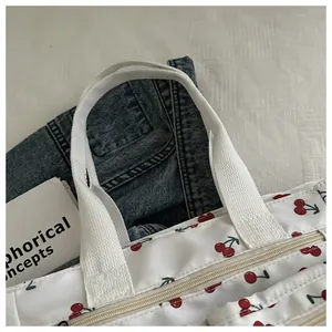 Close-up of cherry print on white tote bag with zip closure and woven handles
