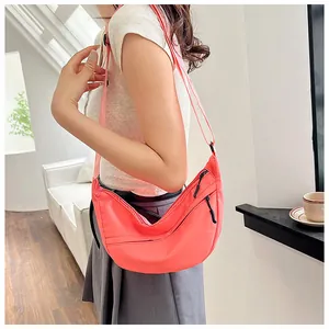 Detailed side view of a coral orange nylon crescent crossbody bag with multi-zipper design