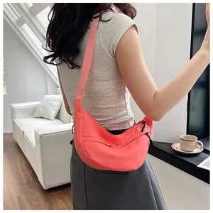 Close-up of coral orange nylon crescent crossbody bag with adjustable wide strap for women