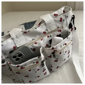 Detailed shot showing phone and earbuds in a multi-pocket cherry print tote bag