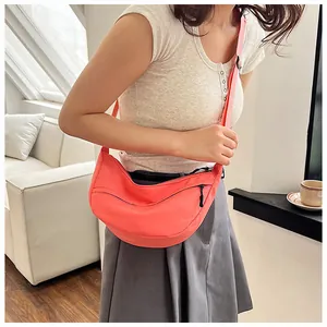 Close-up of coral orange nylon crescent crossbody bag with adjustable strap and zipper