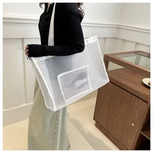 Detalle del bolso tote de malla blanca con textura transparente y bolsillo frontal