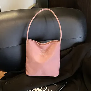 Pink minimalist tote bag with Hope and Future embroidery on a black leather couch