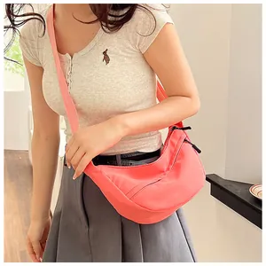 Detail view of pink nylon half-moon crossbody bag shown on model for size and fit