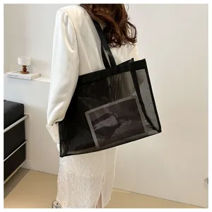 Detalle del bolso tote de malla negra que muestra la transparencia y las correas fuertes