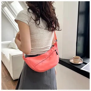 Close-up of a pink crescent nylon crossbody bag worn over a grey skirt in daily setting
