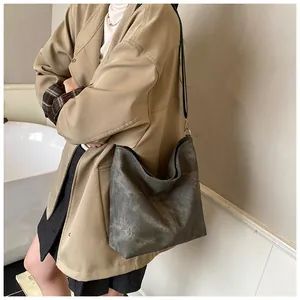 Λεπτομέρεια ανθρακί τσάντας tote με vintage υφή και μαύρο ιμάντα ώμου πάνω στο μοντέλο