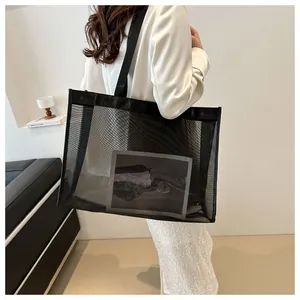 Modelo con un bolso tote de malla negra de gran capacidad y diseño semitransparente