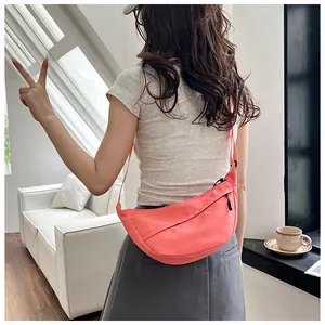 Detail of coral orange nylon crescent crossbody bag with zipper and adjustable strap