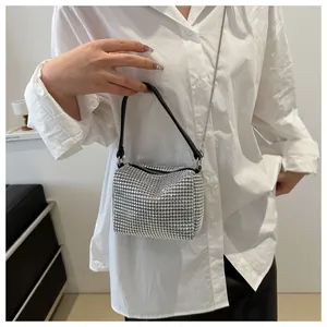 Close-up of sparkling silver rhinestone handbag with elegant metal chain on model