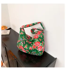 Detailed view of the dark green floral ethnic tote bag with phoenix pattern on a black cabinet