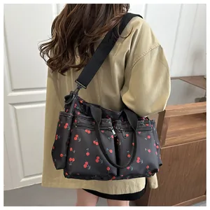 Detail of black cherry print shoulder bag with multiple functional zipper pockets
