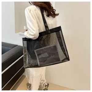 Primer plano del bolso de malla negra con bordes de cuero sintético en un entorno minimalista