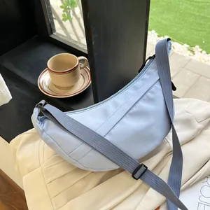 Close-up of a light blue nylon crescent crossbody bag with adjustable wide strap and zip