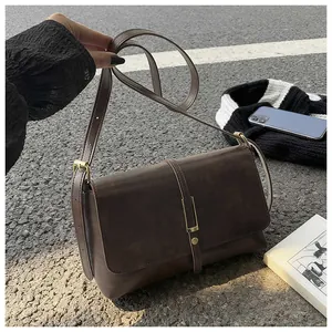 Detail of dark brown vintage small square crossbody bag with metallic buckle and leather texture