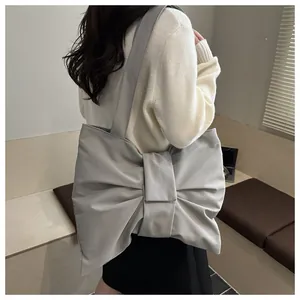 Detail van de grote grijze bow-tote tas op het model voor een eigentijdse en moderne look