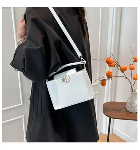 Dettaglio di una borsa bianca in pelle con logo rotondo in metallo argentato sulla patta