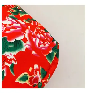 Macro detail of red ethnic floral canvas fabric with vibrant peony pattern and stitching