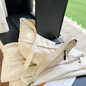 Detail of cream nylon crescent bag showing the zipper and wide adjustable strap
