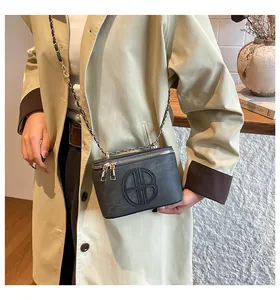 Detail der dunkelgrauen Mini-Kettenbox-Tasche mit goldenen Reißverschlüssen und Logo