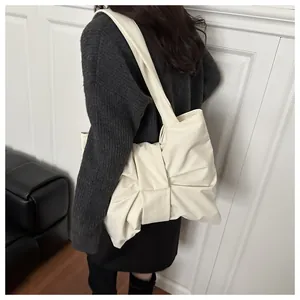 Detailaufnahme einer cremeweißen Schultertasche mit großer Schleife aus weichem Kunstleder
