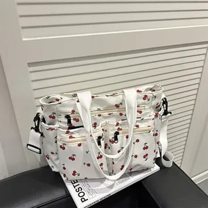 White canvas tote bag with red cherry prints and multiple functional front pockets