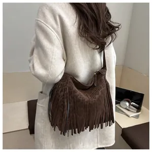 Dettaglio di una borsa hobo marrone con frange e stampa leopardata su un cappotto di lana bianco