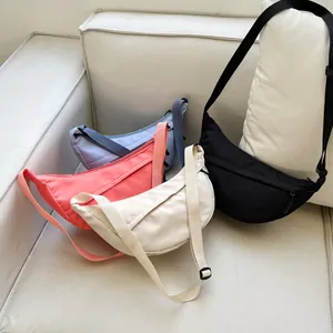 Nylon crescent crossbody bags in purple, pink, beige and black on a sofa
