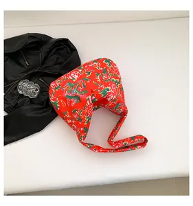 Detail of red floral tote bag with ethnic pattern laid next to black leather jacket