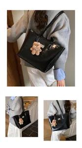 Detalle del bolso tote de charol negro brillante con un lindo colgante de oso de peluche