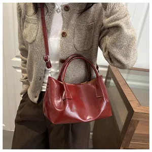 Detail of burgundy glossy pleated handbag with silver hardware and shoulder strap