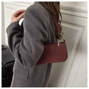 Detail showing a stylish burgundy baguette shoulder bag with matte texture and silver hardware