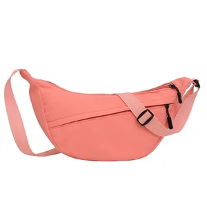 Minimalist pink crescent nylon crossbody bag with adjustable shoulder strap and zippers