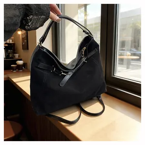 Detail of black canvas hobo bag with leather trim and gold zippers in a cafe setting