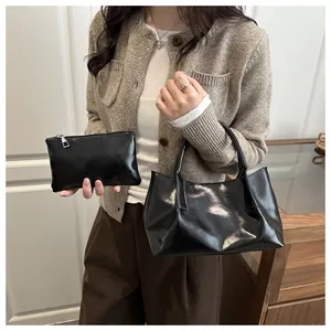 Detail view of black glossy faux leather tote bag and matching small square zipper pouch