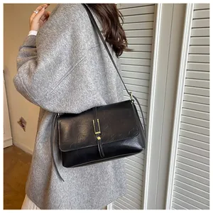 Side view of a vintage black leather small square crossbody bag worn by a model