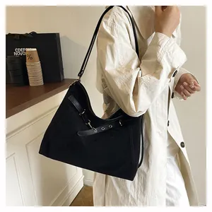 Detail of a black large-capacity tote bag featuring sleek leather straps and metal eyelets
