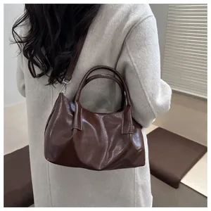 Detail of a dark brown pleated leather handbag with silver hardware and detachable strap