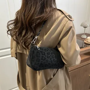 Chic black leopard print shoulder bag worn with khaki coat in cozy cafe setting