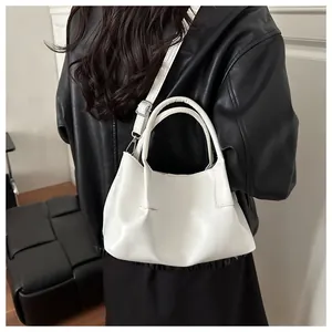 Close-up of white pleated crossbody bag featuring polished faux leather and adjustable strap