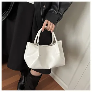 Detailed view of a white glossy handbag with stylish pleats and soft round handles