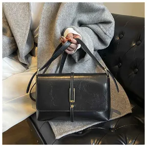 Detail of vintage black leather crossbody bag with elegant gold hardware and metal lock