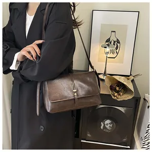 Macro shot of dark brown vintage leather crossbody bag with minimalist gold hardware