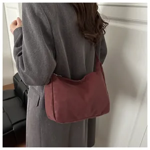 Model view of burgundy crescent hobo bag with dark grey wool coat in minimalist indoor scene