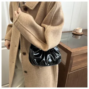 Détail du sac nuage plissé noir brillant porté avec un manteau d'hiver en laine