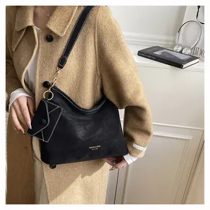 Dettaglio della borsa hobo nera con mini pochette a busta e cuciture bianche a contrasto