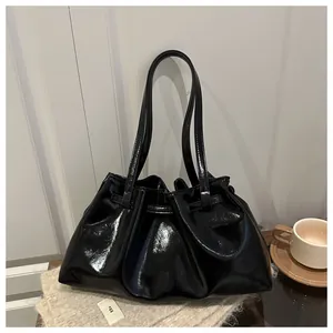 Detail einer schwarzen glänzenden Falten-Schultertasche mit Lackoptik und Egg-Label